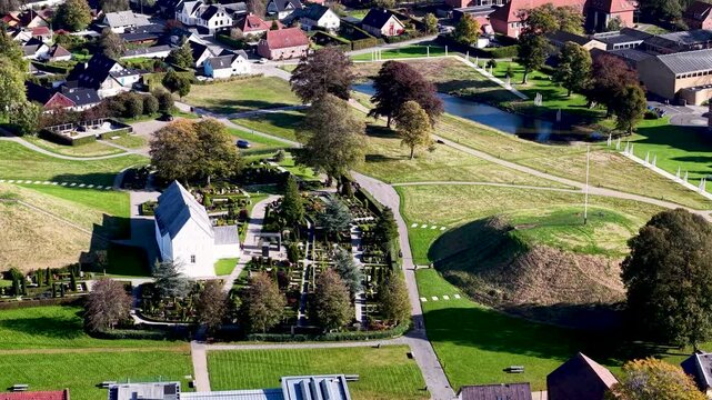 Aerial drone view of Jelling Church, cemetery, and Viking burial mounds within UNESCO heritage landscape in Denmark