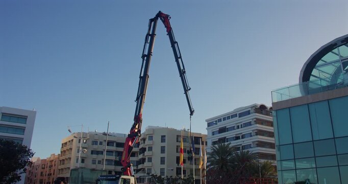 Extra wide shot of a lorry crane lifting up a pane of glass onto a hotel