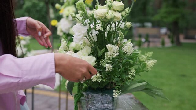 Professional female florist assembling a luxury white flower centerpiece outdoors