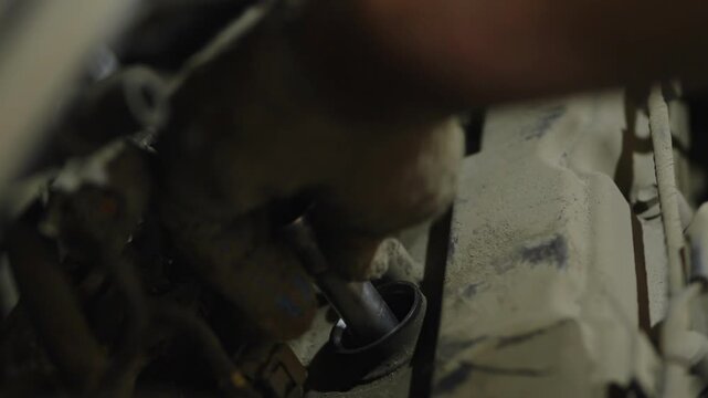  A mechanic tightening a bolt with socket wrench inside engine bay