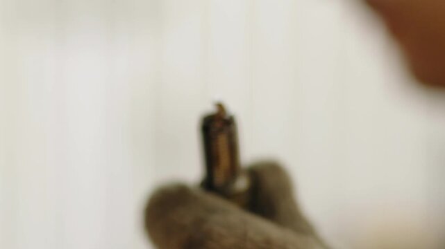 Gloved hand holds a dirty car spark plug covered in engine oil sludge.