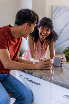 Man sitting and woman leaning counter chatting sparking animated biz chart over mugs for metrics