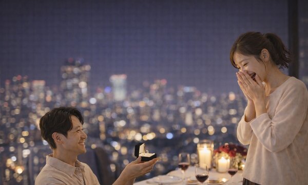 夜景を背景にプロポーズする男性と驚き喜ぶ女性 ロマンチックな婚約シーン