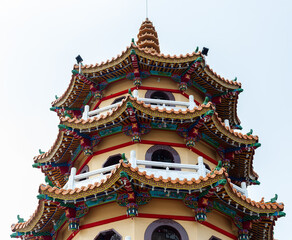 Fototapeta premium Dragon and Tiger Pagodas rise above Lotus Pond in Kaohsiung. Iconic Taiwanese landmarks blending traditional Taiwanese architecture. Colorful multi-tiered towers with intricate detailing.