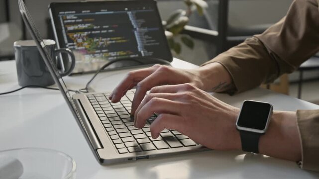 Close-up shot of unknown male developer typing code on laptop keyboard in office. Footage for software engineering, IT startup, and cybersecurity commercial projects