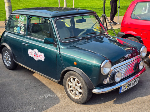 Piatra Neamt, Romania - June 7, 2025: View of a dark green 1989 Mini Cooper, showcasing its classic design, chrome grille, round headlights, and white stripe.