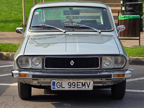 Piatra Neamt, Romania - June 7, 2025: A metallic silver Renault 12, a classic and iconic sedan, is parked, showcasing its distinctive front grille and headlights in clear detail.