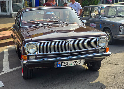 Piatra Neamt, Romania - June 7, 2025: Front view of a classic burgundy 1972 GAZ-24 Volga car, parked on a street at  a car exhibition.