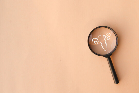 close up top view on magnify with uterus symbol on beige background represent about women health checkup and lifestyle for health and wellness concept