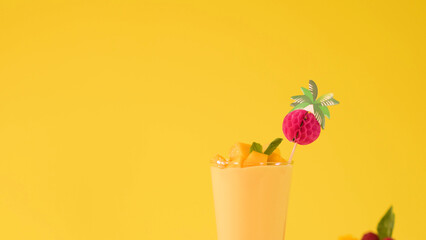 Tropical Mango Smoothie with Fruit Garnish on Bright Yellow Background © blueringmedia