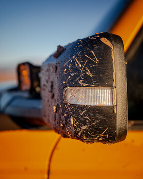 Mud splattered truck side mirror at sunset