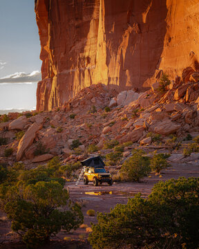 Orange SUV with rooftop tent in a desert canyon