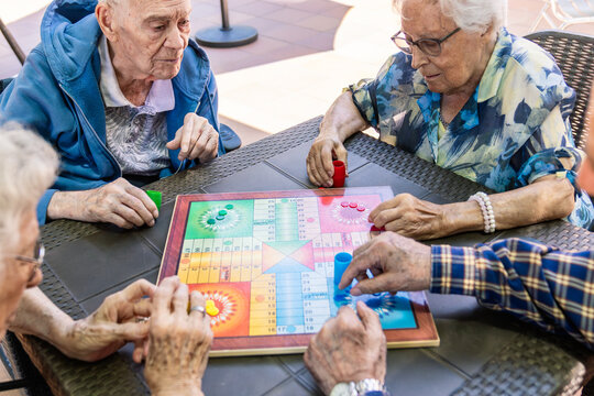 Senior adults enjoying a board game together at a nursing home, fostering social connection and mental engagement during leisure time