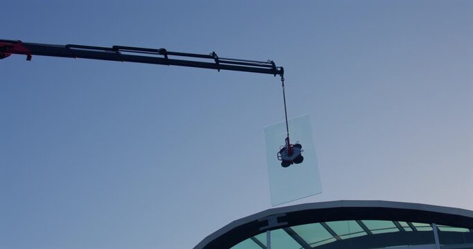 mid Shot of a lorry crane lifting And swinging a pane of glass onto a hotel