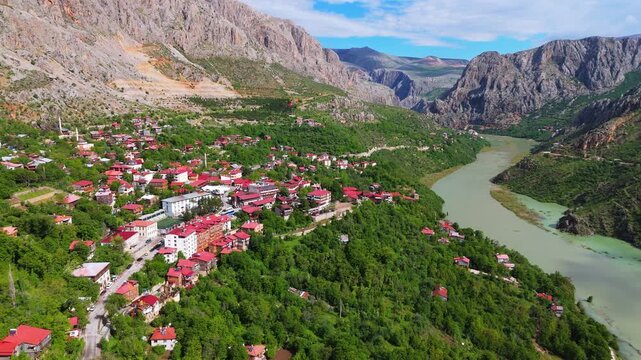 Wide aerial view of Kemaliye town and the winding Euphrates River flowing through a deep valley. Picturesque mountain landscape, traditional red roof houses and green nature in Turkey.