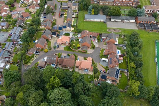 Aerial view of detached family homes and private gardens beside Silcoates School in Wakefield West Yorkshire showing a quiet residential cul de sac mature woodland and recreational grounds from above