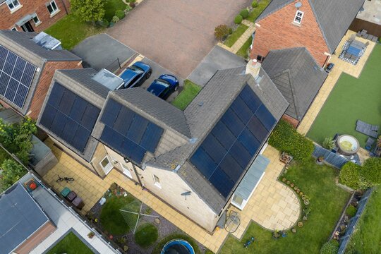 Aerial view of a modern detached family home in Wakefield West Yorkshire featuring extensive rooftop solar panel installation landscaped gardens paved patio areas and sustainable residential living