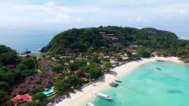 Beautiful drone footage of a beach on Koh Phi Phi in Thailand. Boats are anchored in the turquoise blue water.