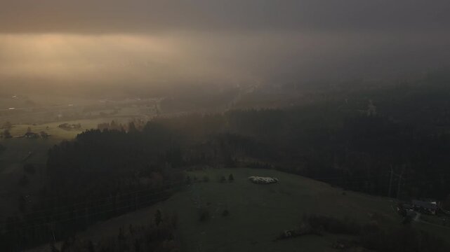 Low clouds drift across the landscape as warm orange dawn light emerges over Jablunkov Fortress in the Czech Republic. Atmospheric aerial travel footage.