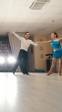 Young beautiful man and woman dancing and practicing Latin dance in costumes in the Studio