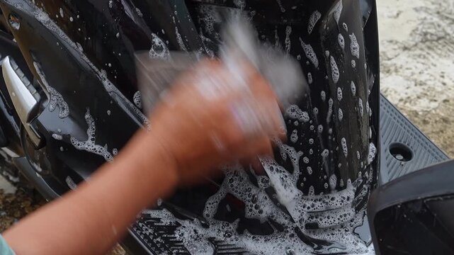 Close-up Hand Washing Motorcycle Chain with chamois cloth in Outdoor Garage