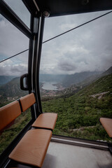 Obraz premium Inside view of a cable car cabin with a breathtaking panoramic outlook of mountains, sea bay, and clouds.