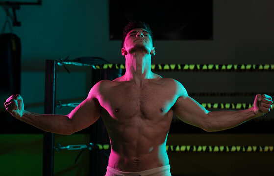 Triumphant Shirtless Boxer Posing in Boxing Ring Showing Muscles and Victory After Training