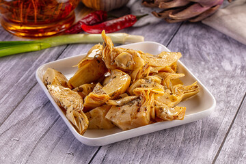 Obraz premium Marinated artichoke hearts with herbs and chili peppers on white plate