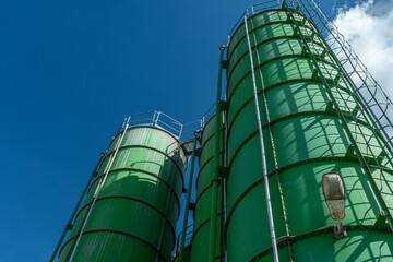 Green industrial cement silos at concrete batching plant symbolizing construction growth, infrastructure development and urban expansion © kalyanby