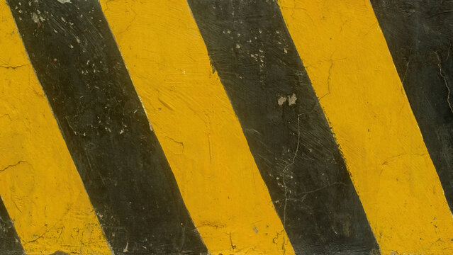 Yellow and black diagonal stripes on concrete wall texture background for industrial hazard warning sign