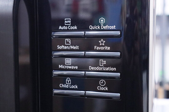 Close up of a black microwave control panel showing electronic push buttons with functional mode text and white line icons