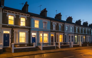 Obraz premium Warmly Illuminated Victorian Terraced Houses Beneath a Deep Blue Cozy Night Sky