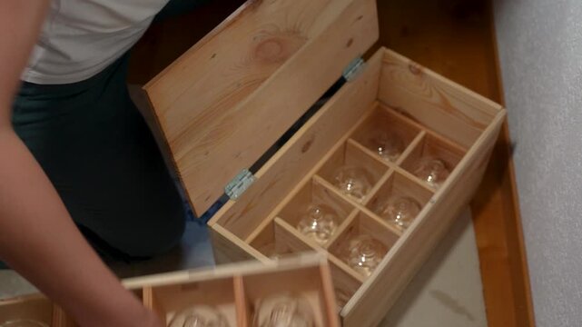 Hand picking glass cups from a wooden box for vacuum cupping therapy, showing wellness treatment tools in a health and relaxation session.