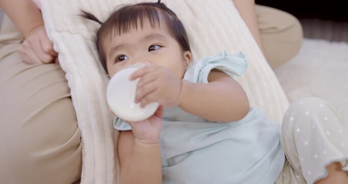 Asian toddler girl smiling happily while holding milk bottle, joyful childhood moment expressing love, comfort, playful energy, warm family care, early learning development and happiness at home