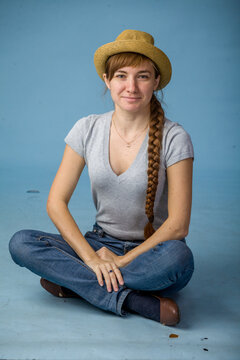 Young woman sitting cross-legged and smiling against blue background  