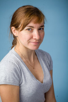 Young woman smiling while sitting against a blue background  