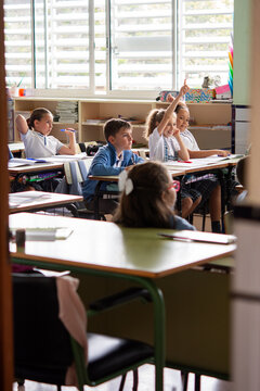 Elementary School Students Raising Hands to Answer Question in Classroom