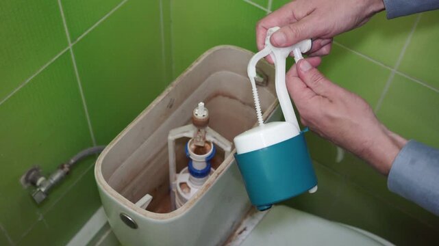 Replacing toilet tank mechanism, home maintenance and plumbing repair, Plumber installing a new float fill valve into a toilet cistern.