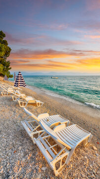 Amazing Sun loungers and beach umbrellas at sunset on the beach of Gradac in Makarska riviera.