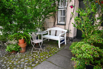 Seating area with a white bench next to the entry door in a small front yard garden at a historic house in the old town, nature in the city, selected focus © Maren Winter