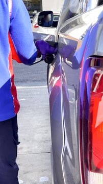Vertical, petrol attendant filling up vehicle with gas at fuel station