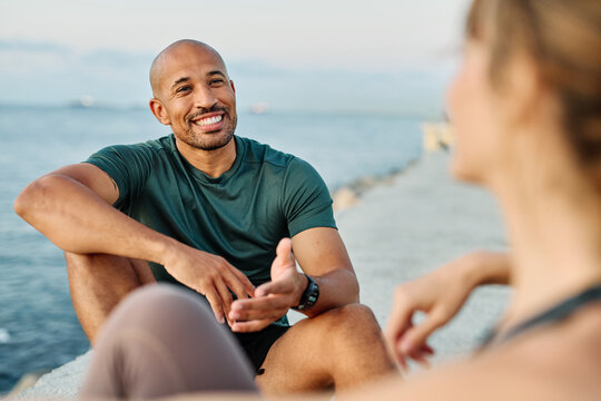 Smiling active young couple jogging exercising and having fun and laughing together taking a break after walking and running in the park, fitness and healhty living concept
