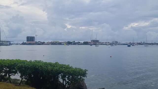 View over Simpson Bay Lagoon on Sint Maarten on a calm overcast day, with sailing boats and catamarans anchored in tranquil grey waters under a cloudy sky