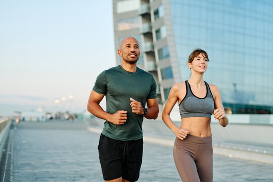 Couple jogging along waterfront pathway at sunset creating a healthy lifestyle