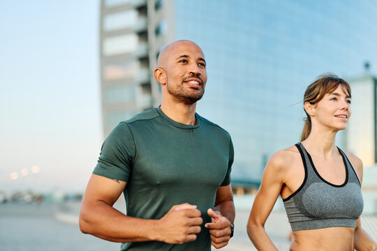 Couple jogging along waterfront pathway at sunset creating a healthy lifestyle