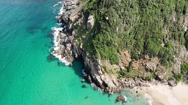 Cinematic Aerial Drone View at 45 Degrees Over Rocky Cliff and Turquoise Sea Coastline