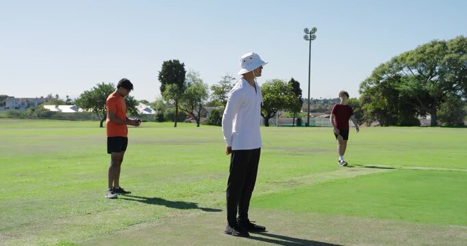 Indian bowler shifting and bowling ball at batsman taking guard at wicket, umpire watching