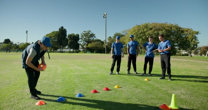 Diverse male sports team in sportswear observing training cones on training field