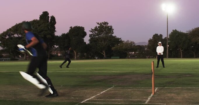 Bowler delivering ball prompts batsman swinging bat on pitch and sprinting crease