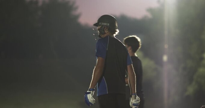 Male batsman with bowler coming swinging bat sprinting under lights, keeper shifting gloves